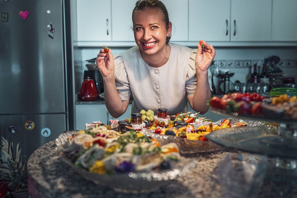 Angelika laughing in the kitchen behind a table of finished platters