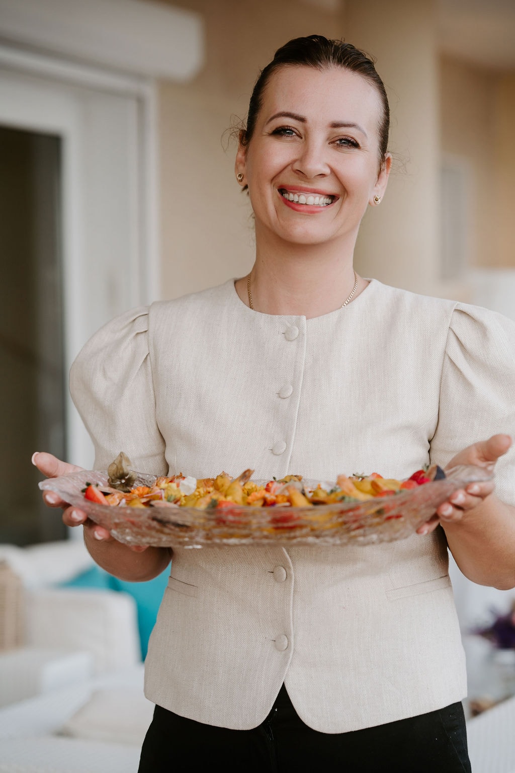 Angelika smiling, holding a platter of colourful food