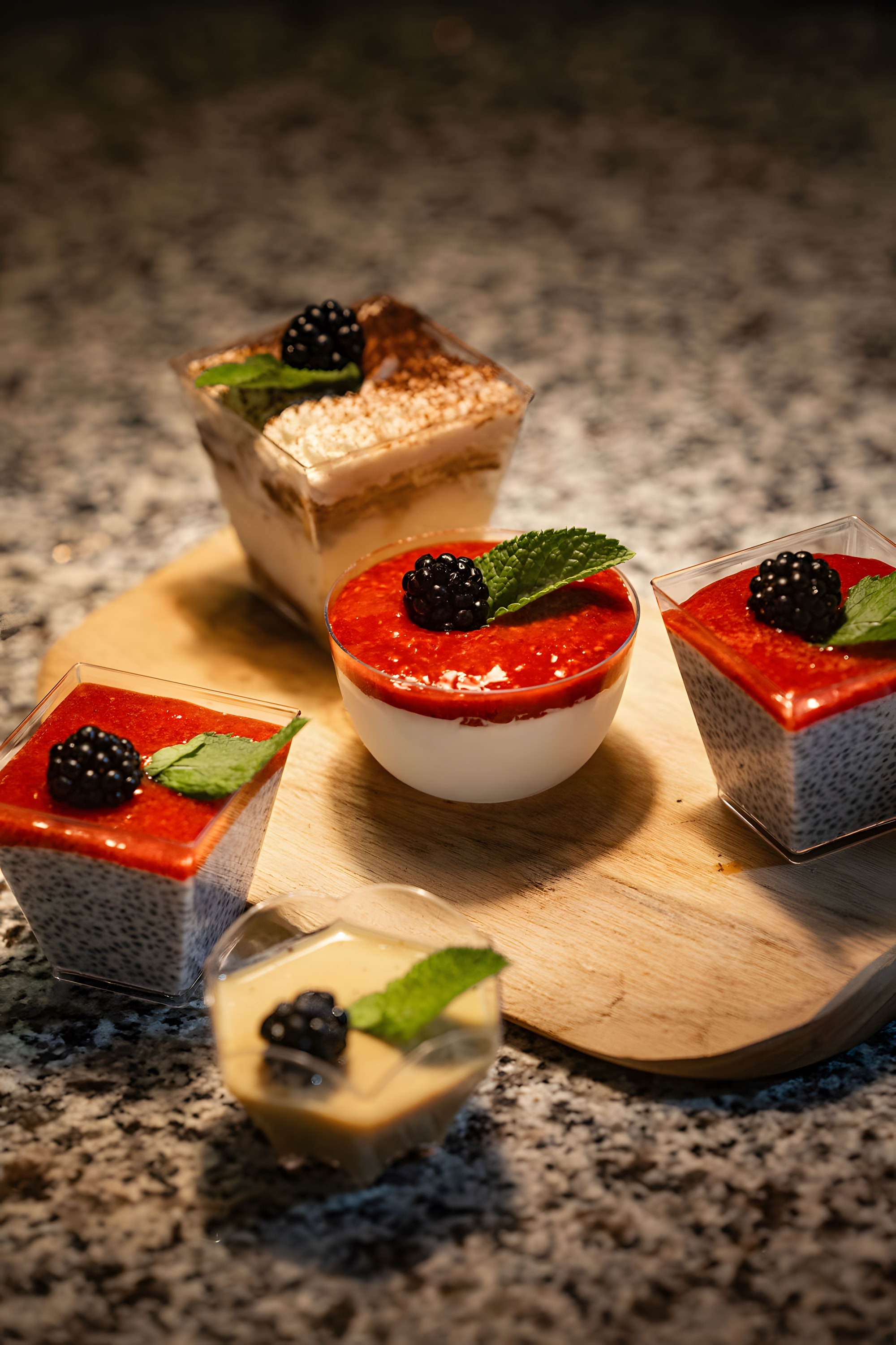A wooden board of plated desserts topped with blackberries and mint