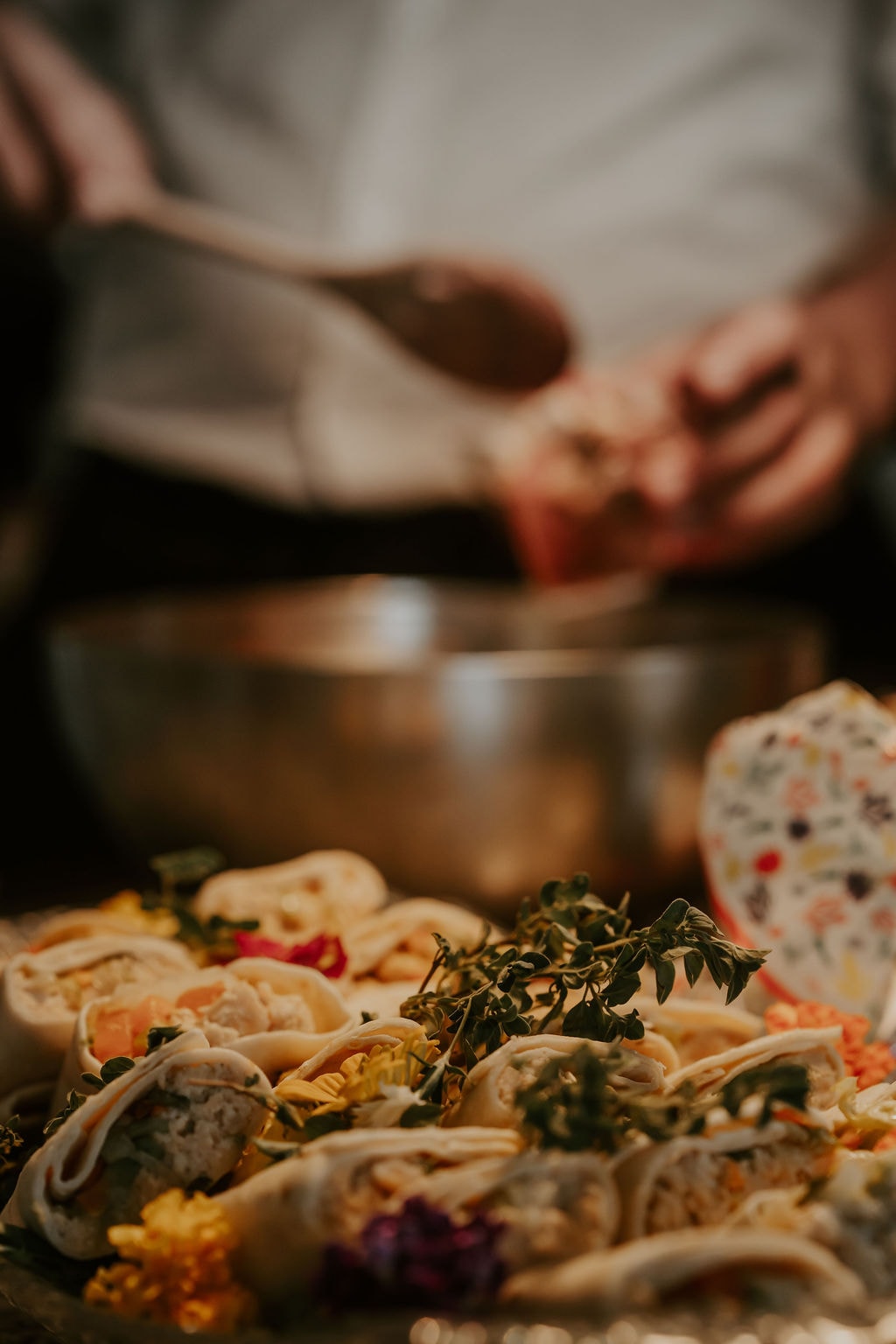 Hands finishing a platter in the kitchen, lit warmly from above