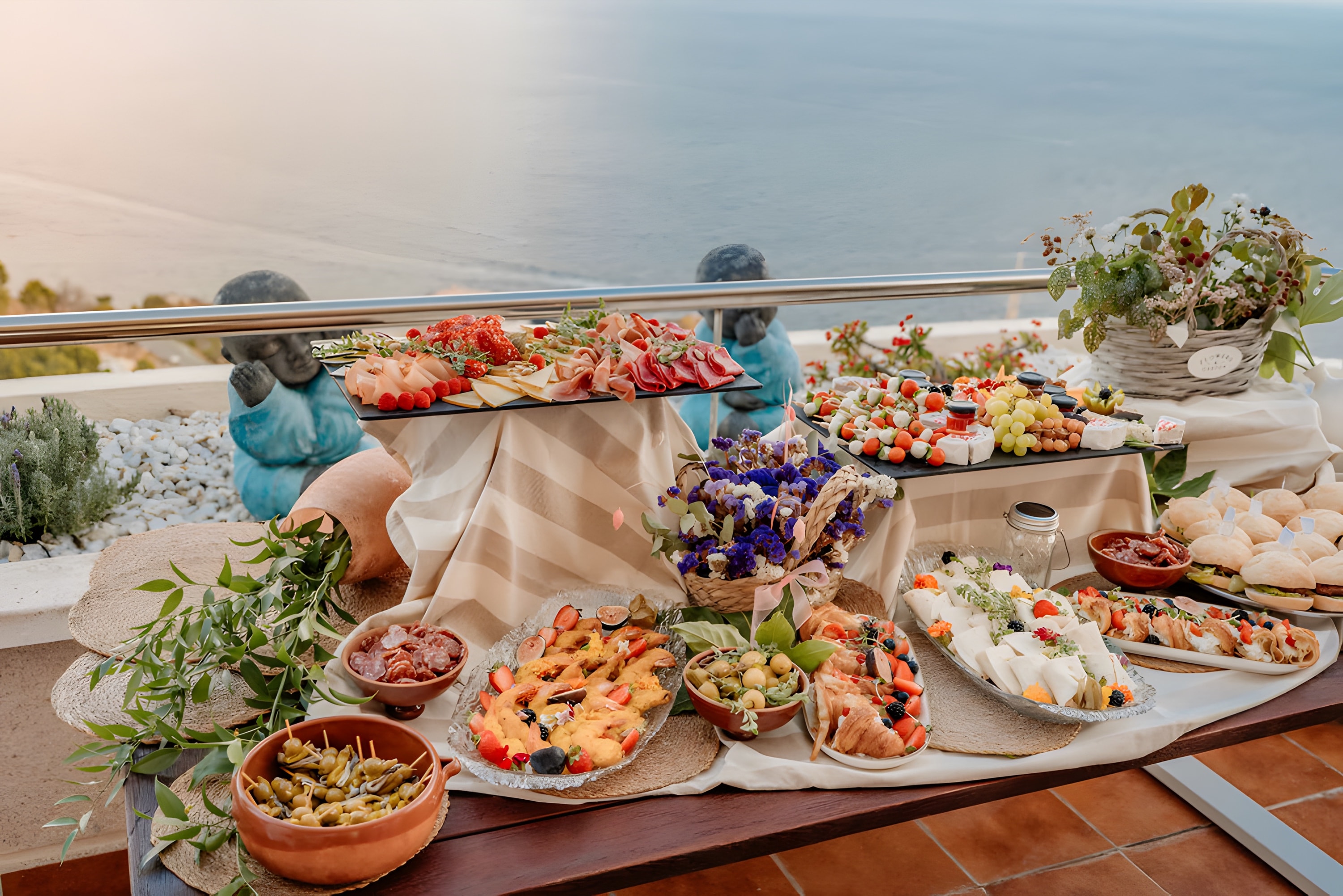 A grazing table with flowers and ceramics laid out along a sea-view terrace