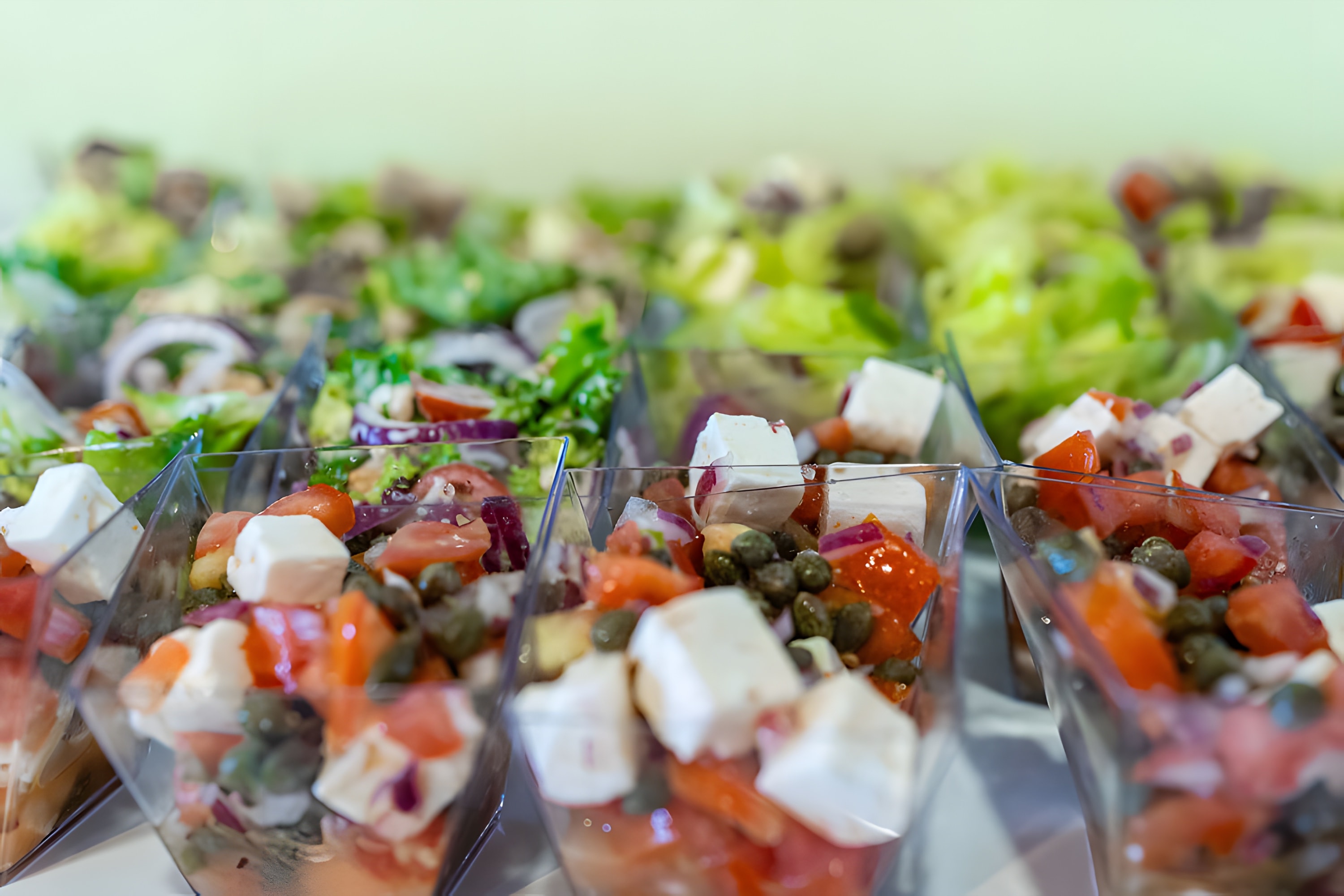 Rows of individual salad verrines with feta and tomato