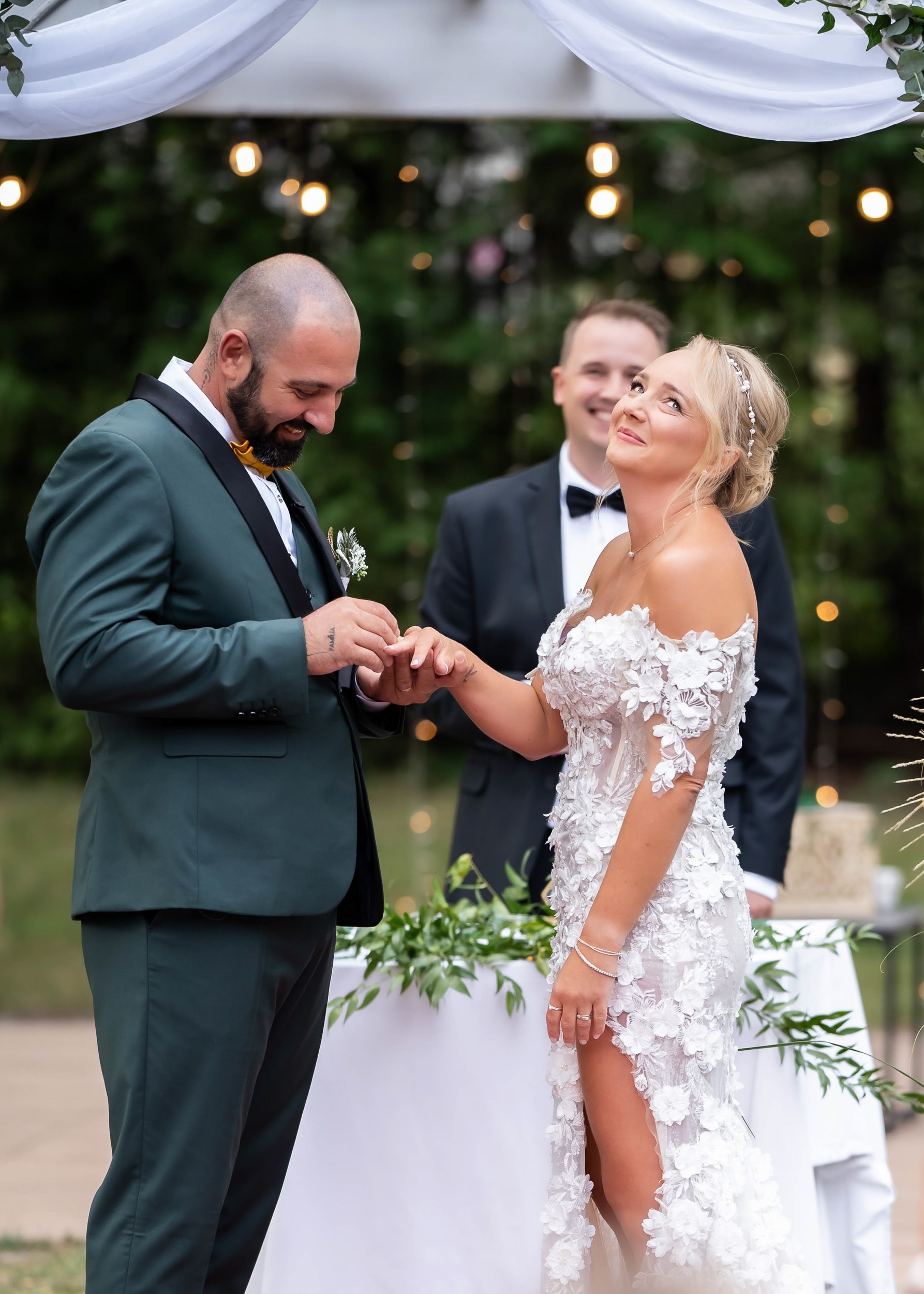 A groom placing a ring on the bride's finger during an outdoor ceremony